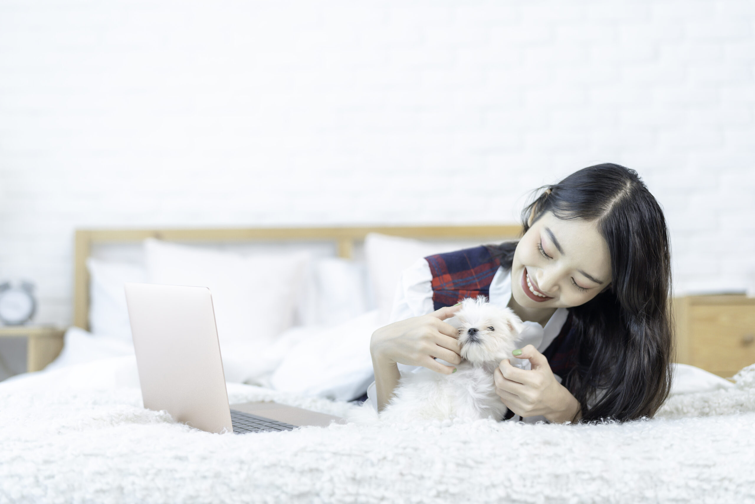 Happy woman with Maltese dog on bed